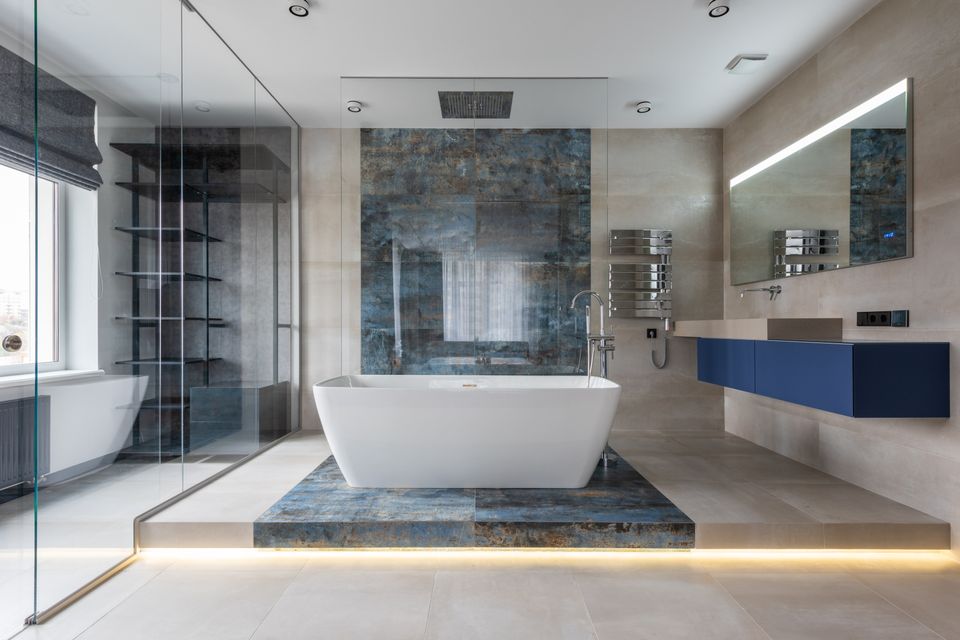 Modernes Badezimmer mit freistehender Badewanne, Glasdusche und beleuchtetem Spiegel